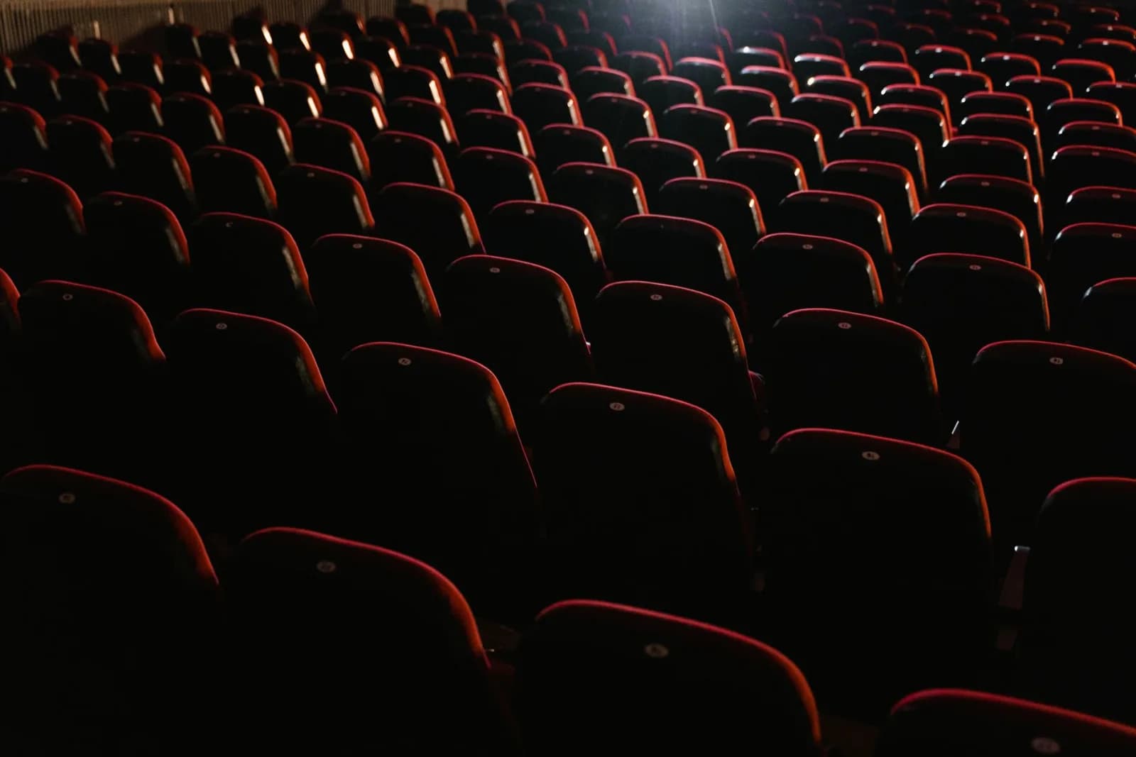 Rows of empty red seats in a dimly lit theater, creating a moody atmosphere.