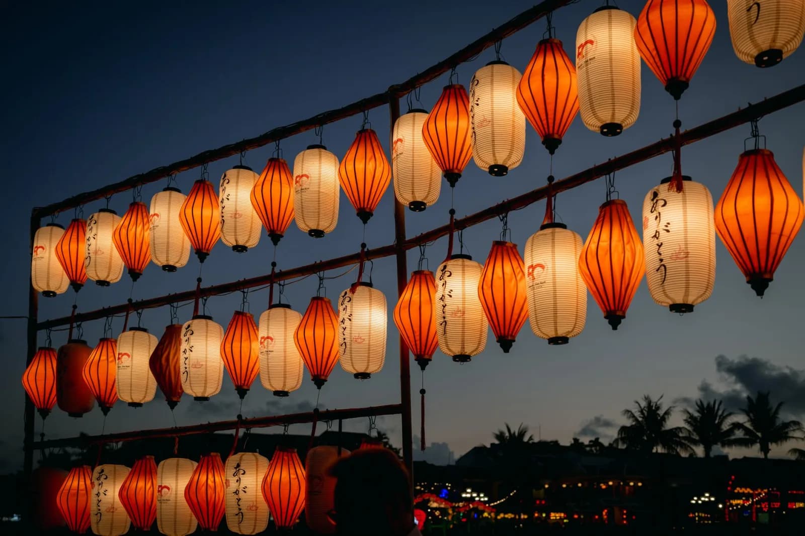 Beautiful display of orange and white lanterns hanging outdoors during a twilight festival.