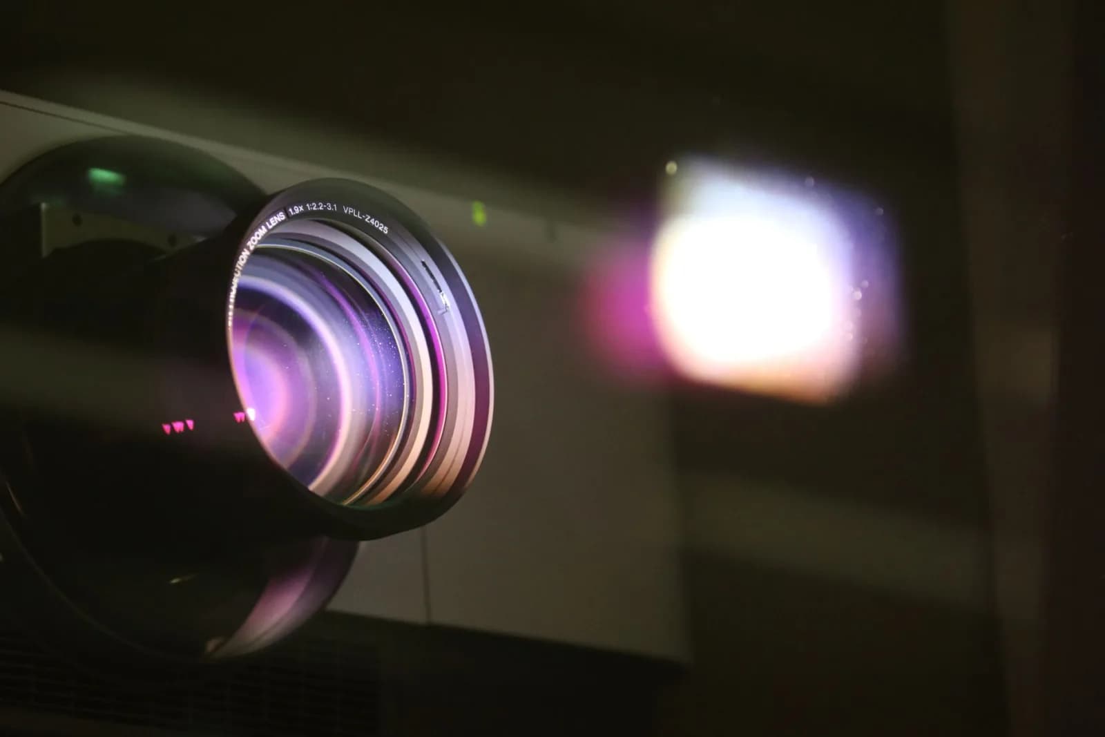 Close-up view of a projector lens with light reflections, highlighting optics and technology.