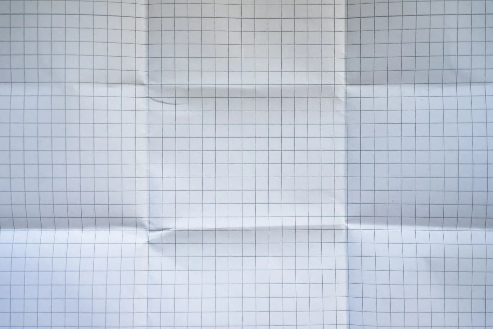 Close-up of a wrinkled grid paper texture with folded creases.