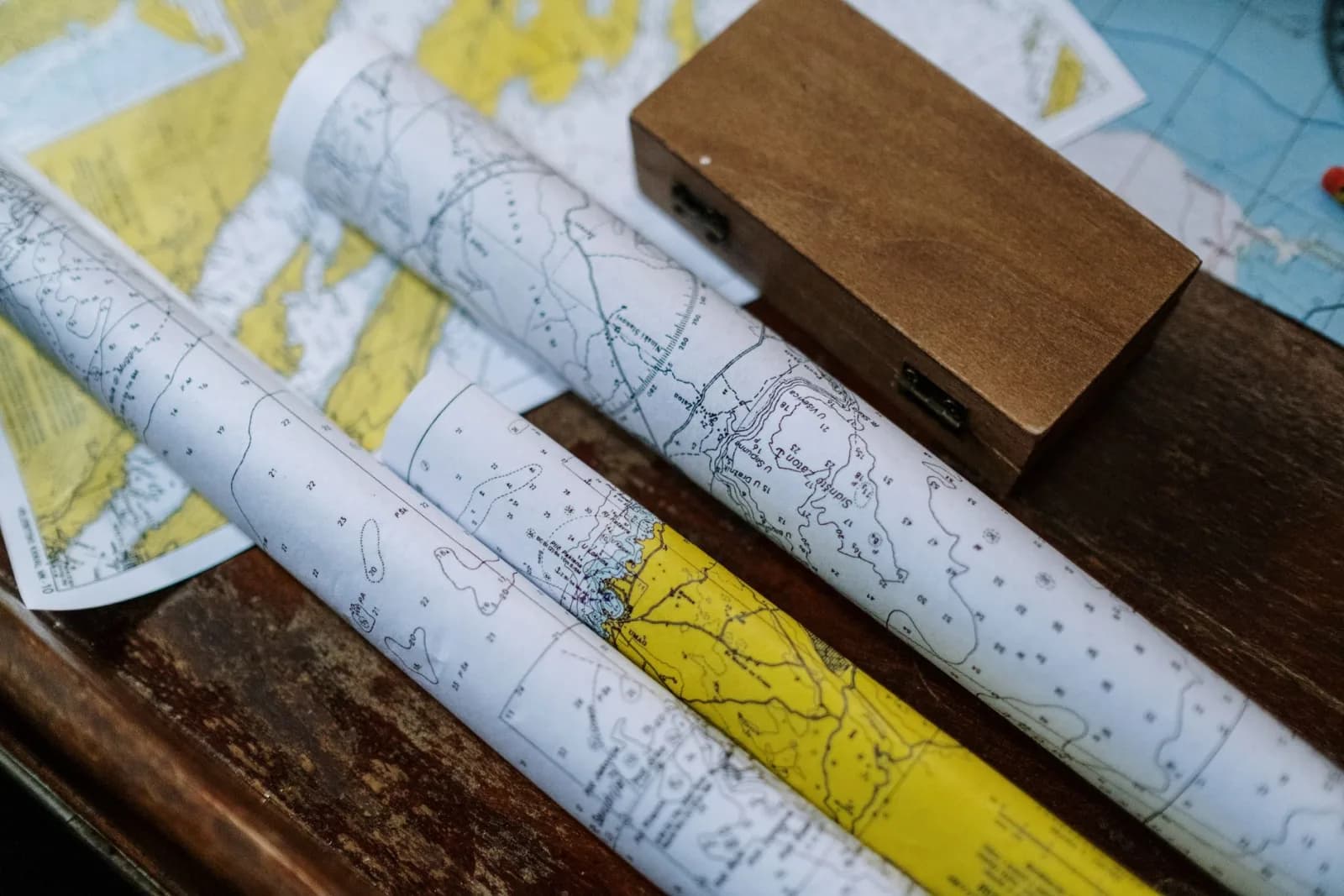 Close-up of rolled nautical maps on a wooden table, perfect for navigation themes.