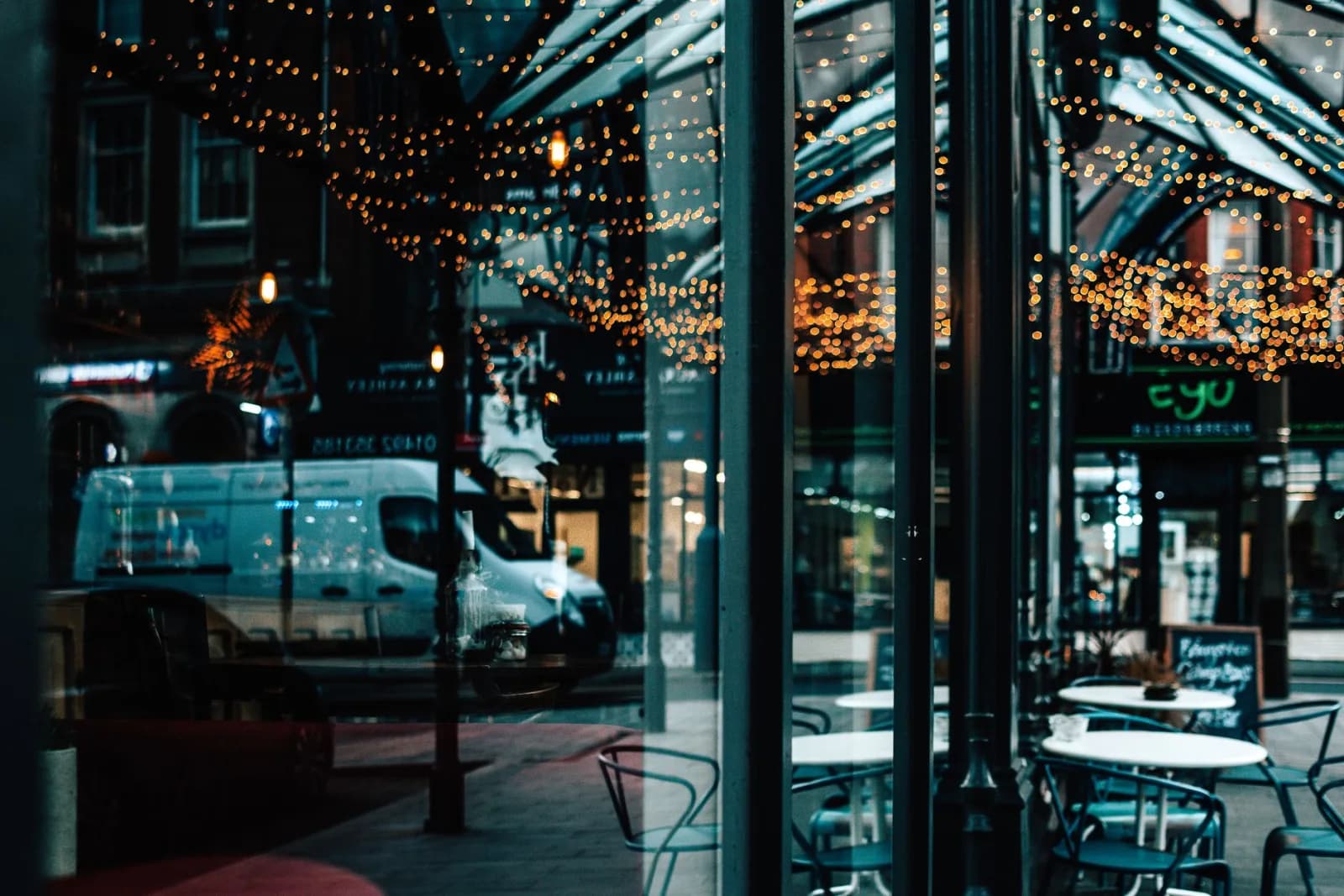 A bustling city scene reflected in a cafe window with warm bokeh lights.