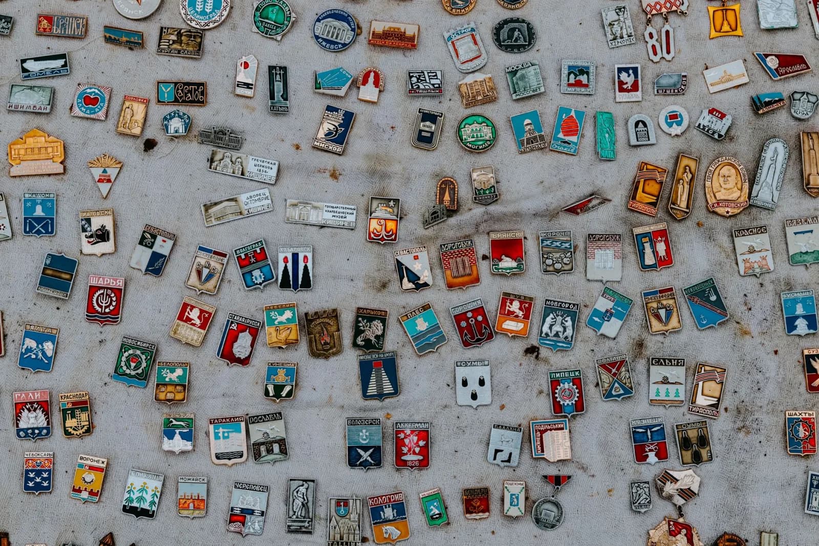 A colorful assortment of vintage enamel pins displayed on a fabric surface.