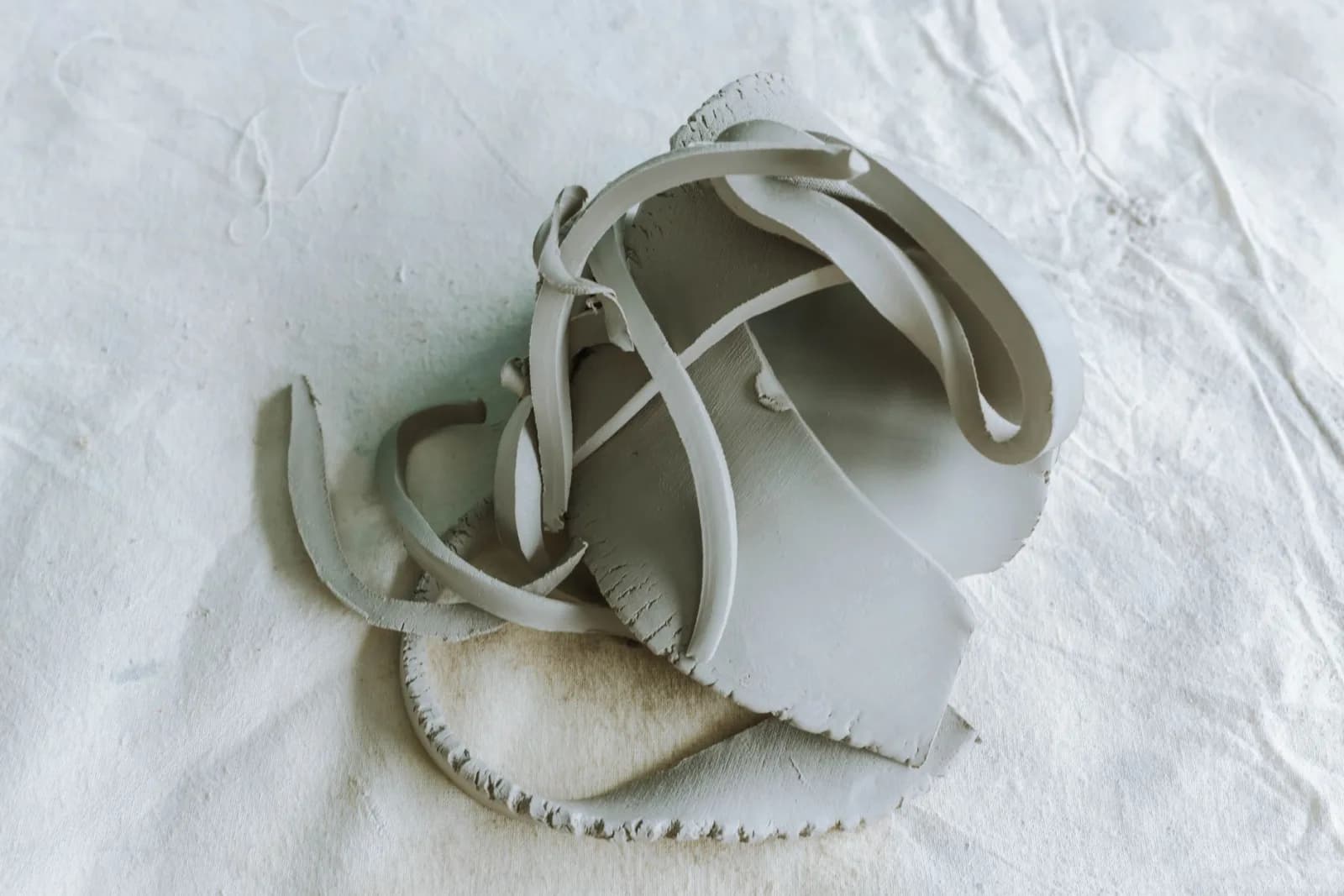 Minimalist close-up of abstract clay sculpture with a serene white background.