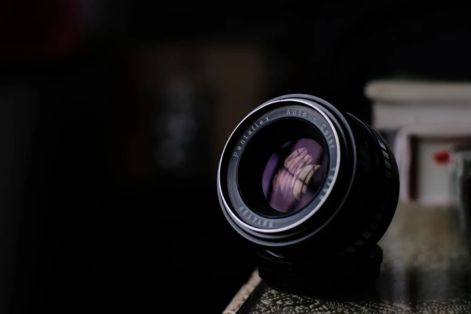 Detailed close-up of a vintage Pentaflex camera lens resting on a table.