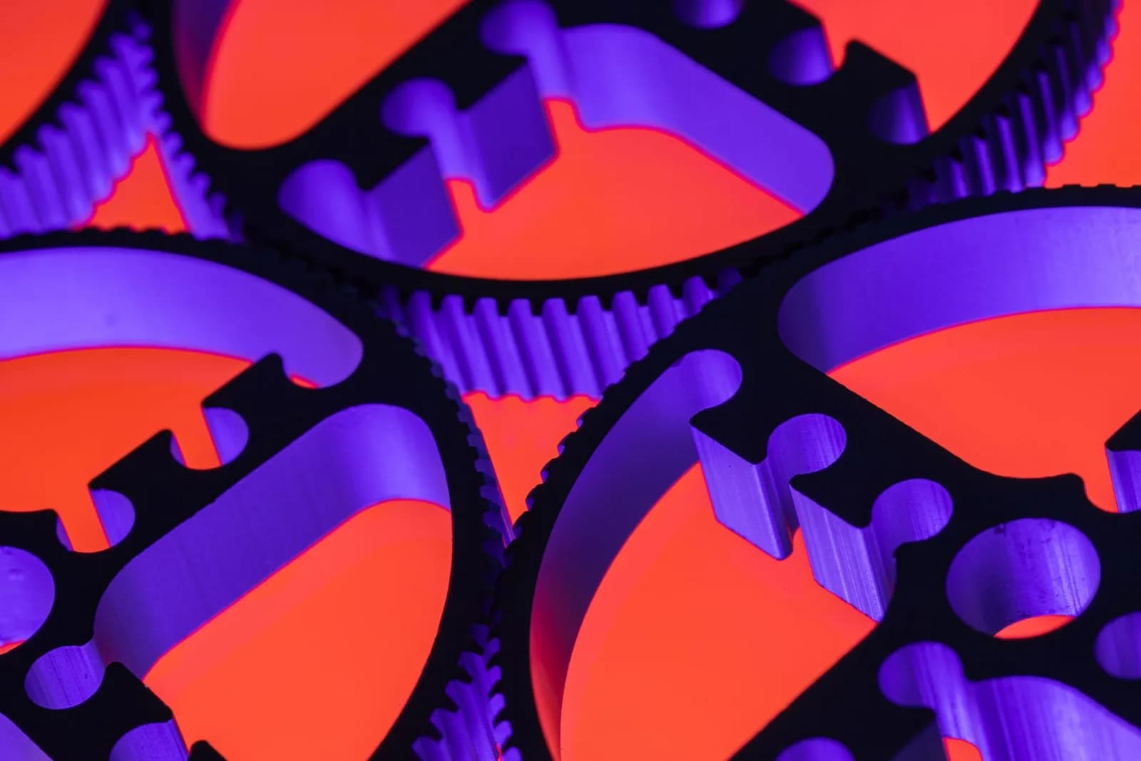 Close-up of interlocking metal gears with vibrant neon lighting, showcasing precision engineering.