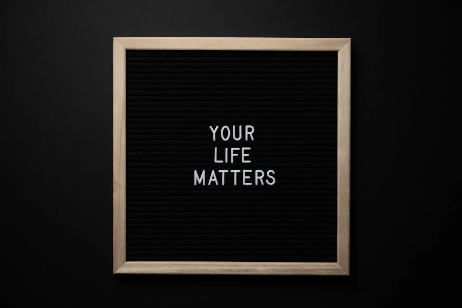From above composition of black chalkboard with wooden frame with text YOUR LIFE MATTERS on center on black background
