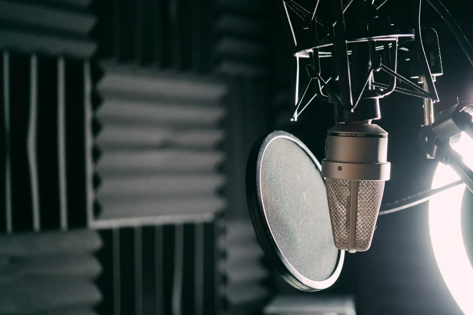 Close-up of a condenser microphone with pop filter in a professional sound studio.