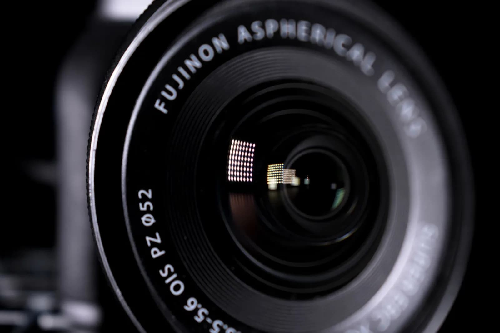Detailed close-up image of a Fujinon aspherical camera lens with reflections.