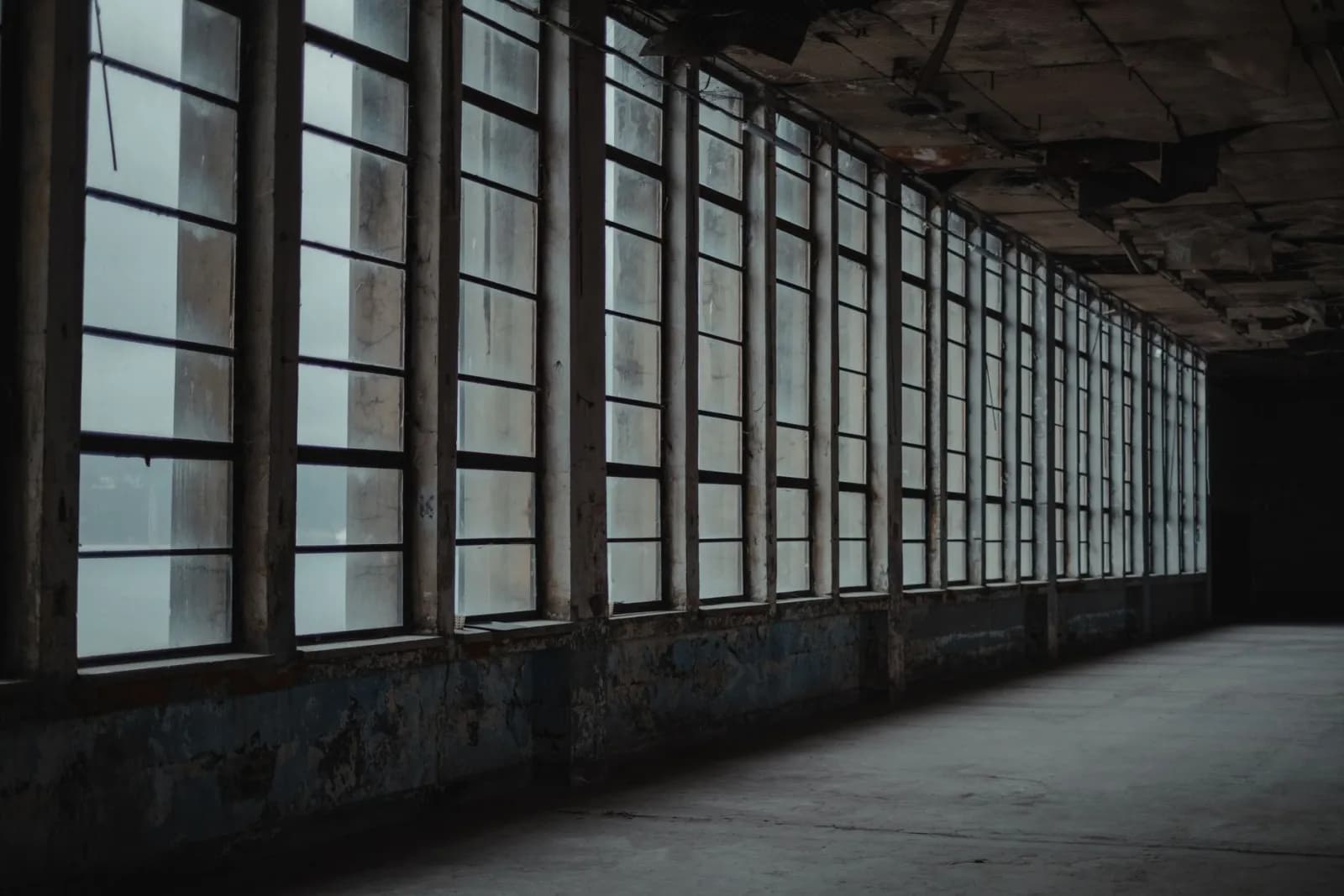 Interior of desolated room with shabby concrete walls and raw of big windows