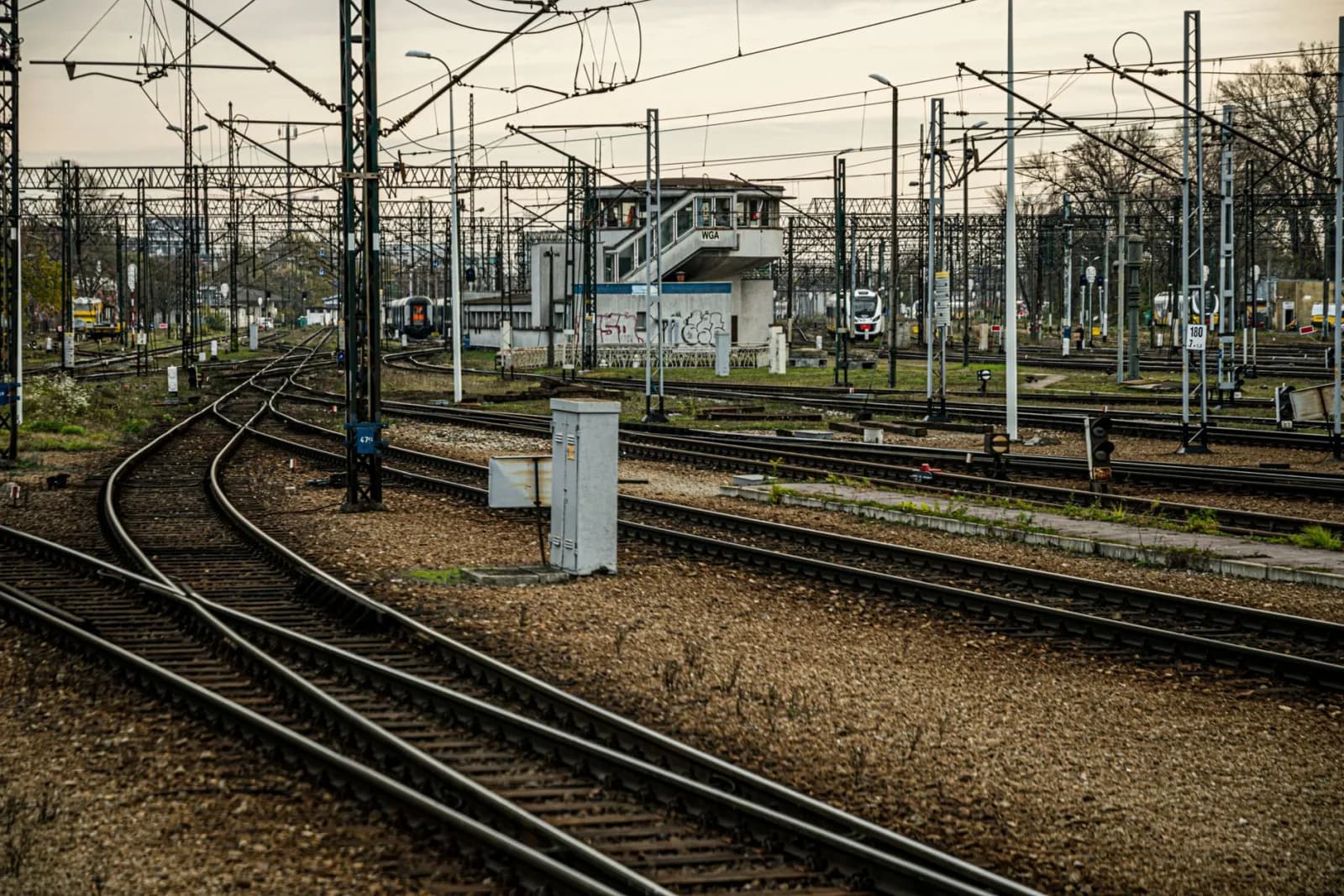 Complex railway junction with tracks and signal systems under a cloudy sky.