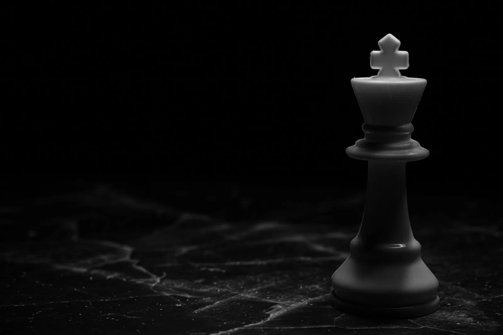 Striking image of a white chess king on a dark marble surface, symbolizing strategy and power.