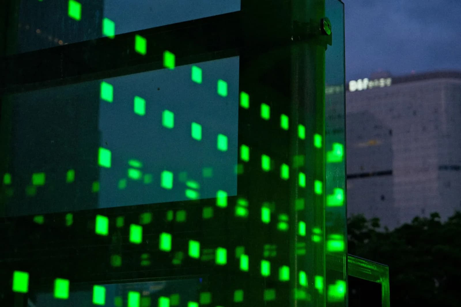Abstract neon green lights reflecting on glass building facade at night.