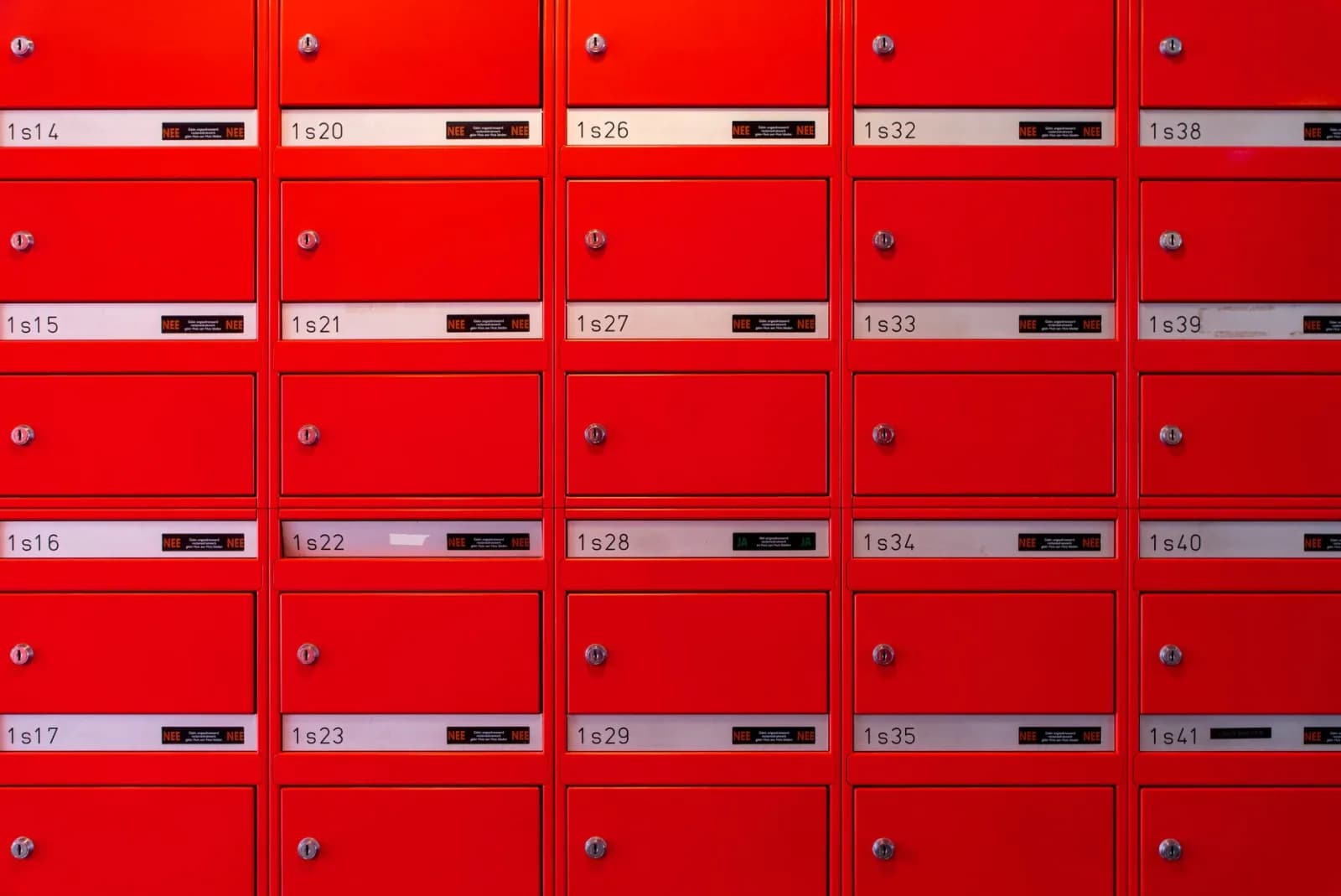 Vibrant red mailboxes arranged in a grid pattern, perfect for urban lifestyle visuals.