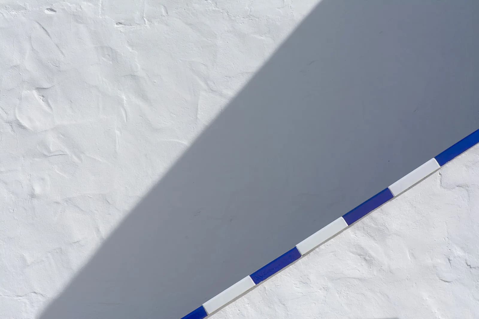 A striking minimalist image showcasing blue and white architectural elements contrasted with shadow play.