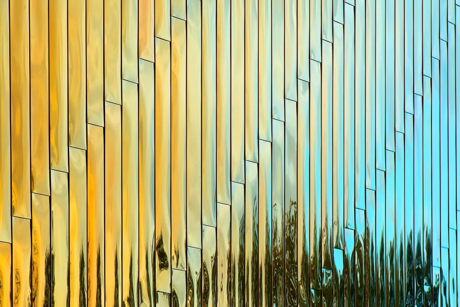 Abstract architectural detail with vertical reflective panels in gold and blue hues.