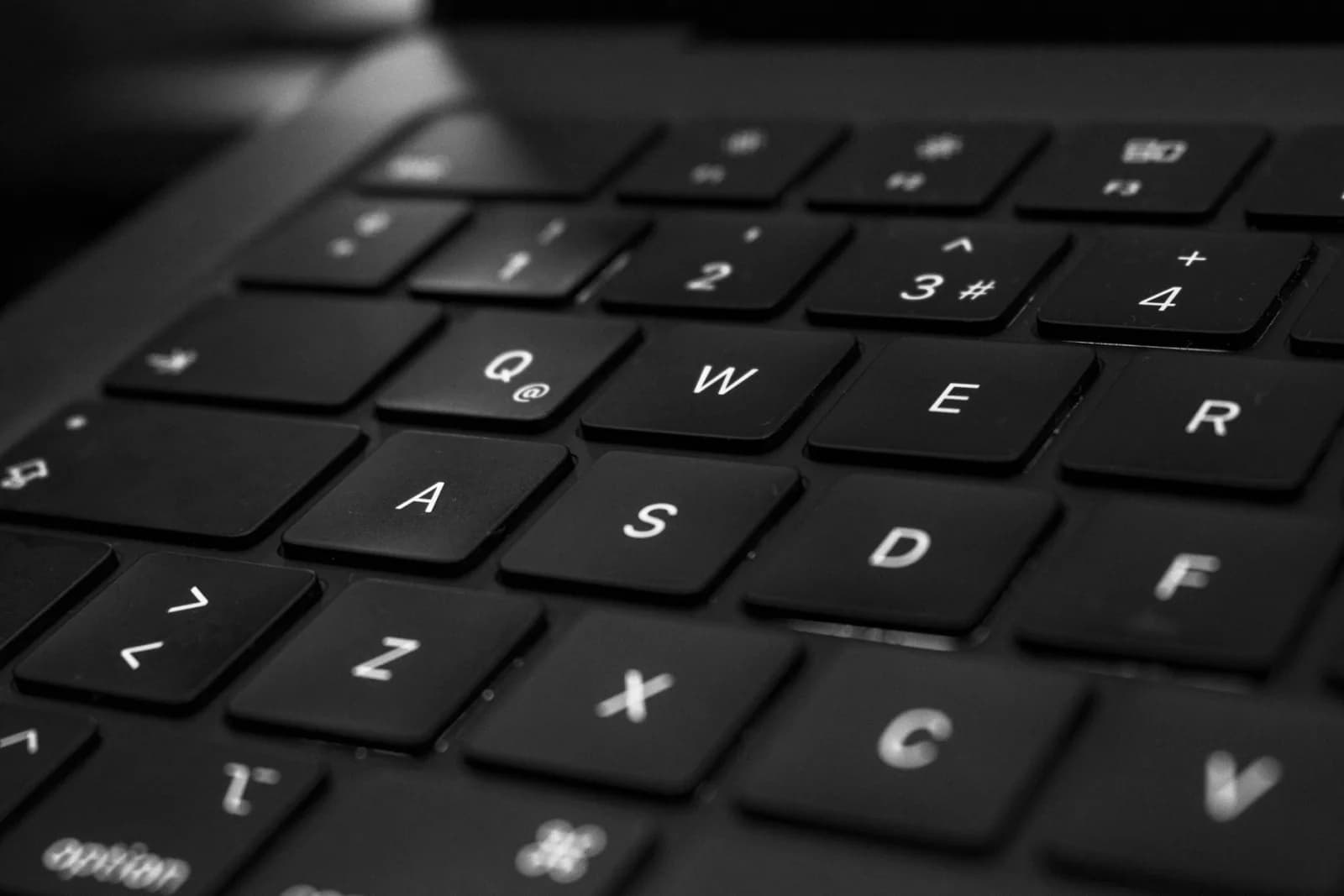 Monochrome close-up of a black keyboard with focus on QWER keys.