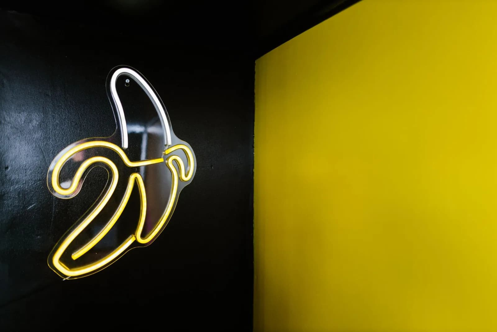 Artistic neon banana sign contrasting against black and yellow walls, creating a vibrant display.