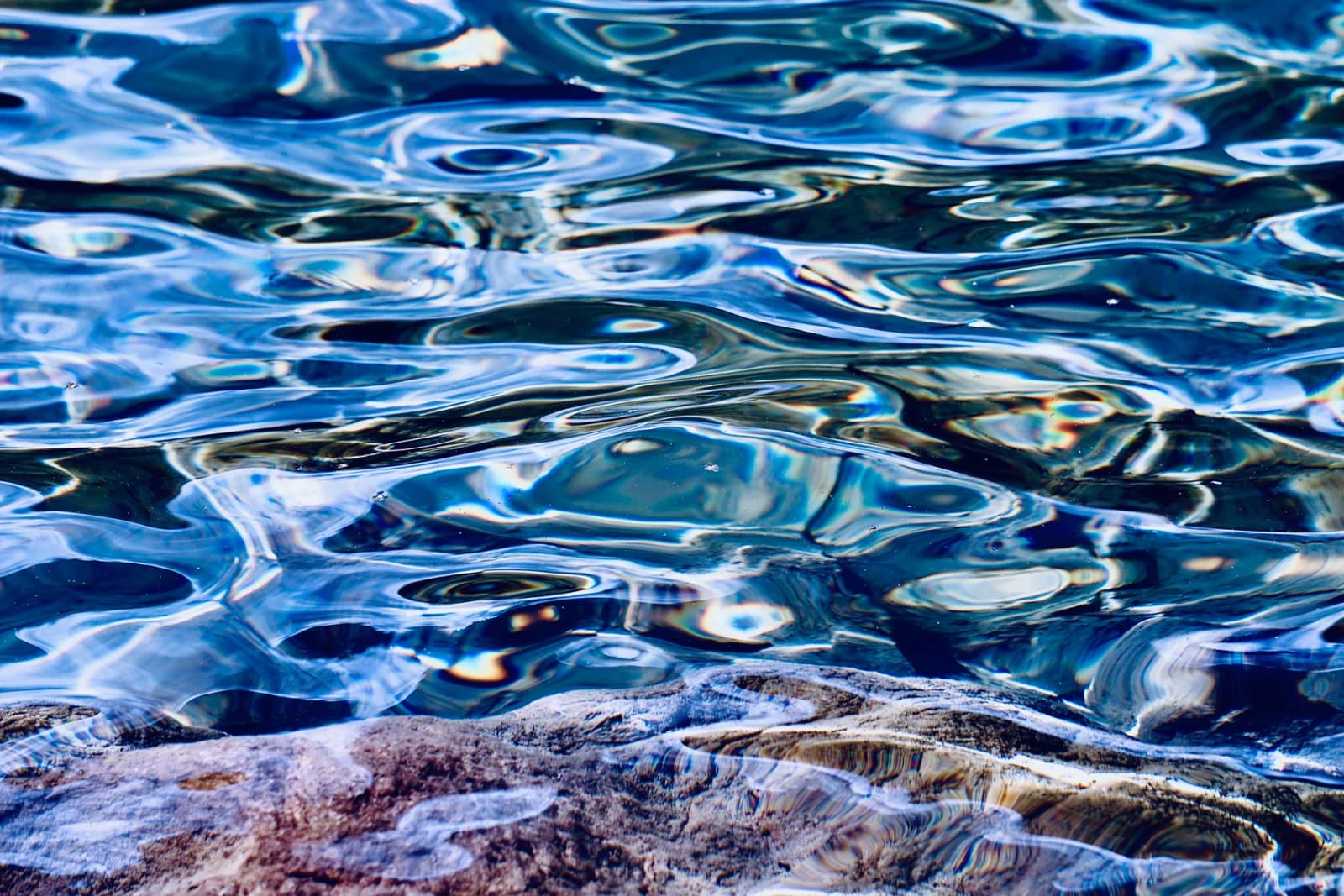 Abstract view of colorful sunlight reflections and ripples on water creating a vibrant pattern.