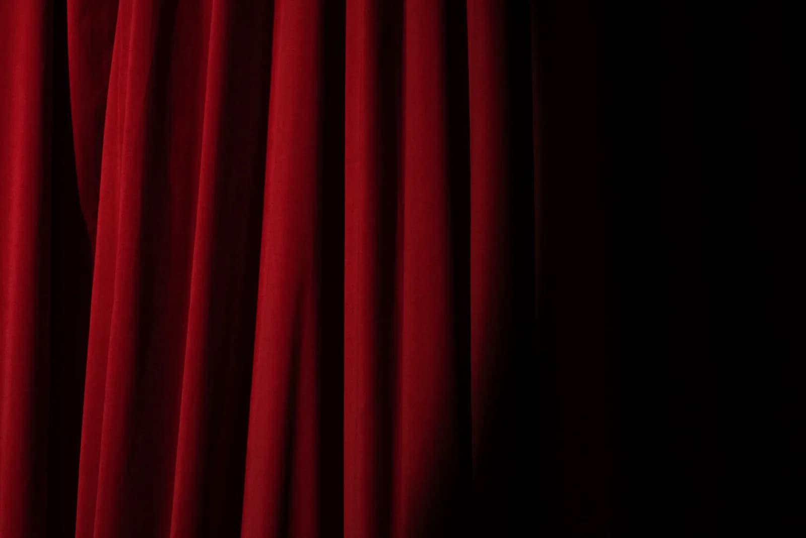 Elegant red velvet curtain with dramatic lighting perfect for theater themes.
