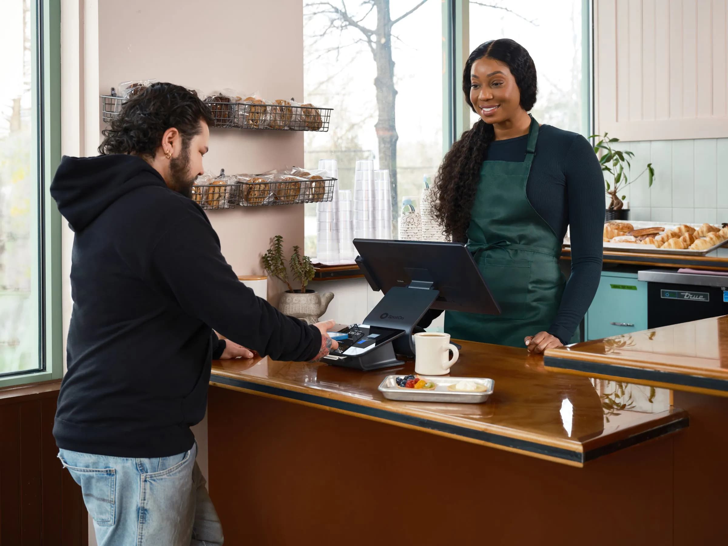 A customer paying at a café counter while the owner serves