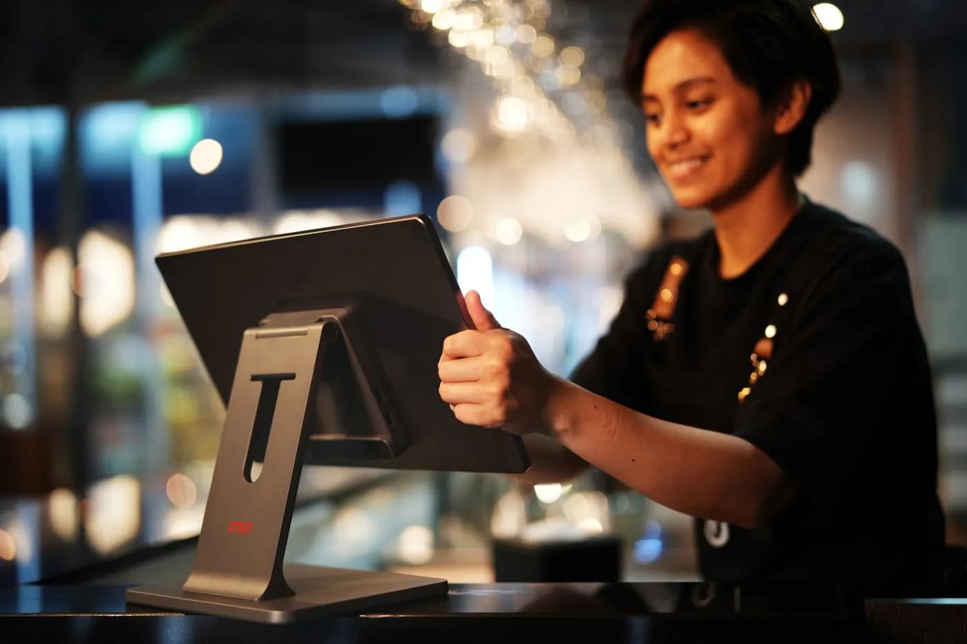 A café owner smiling at the till tablet