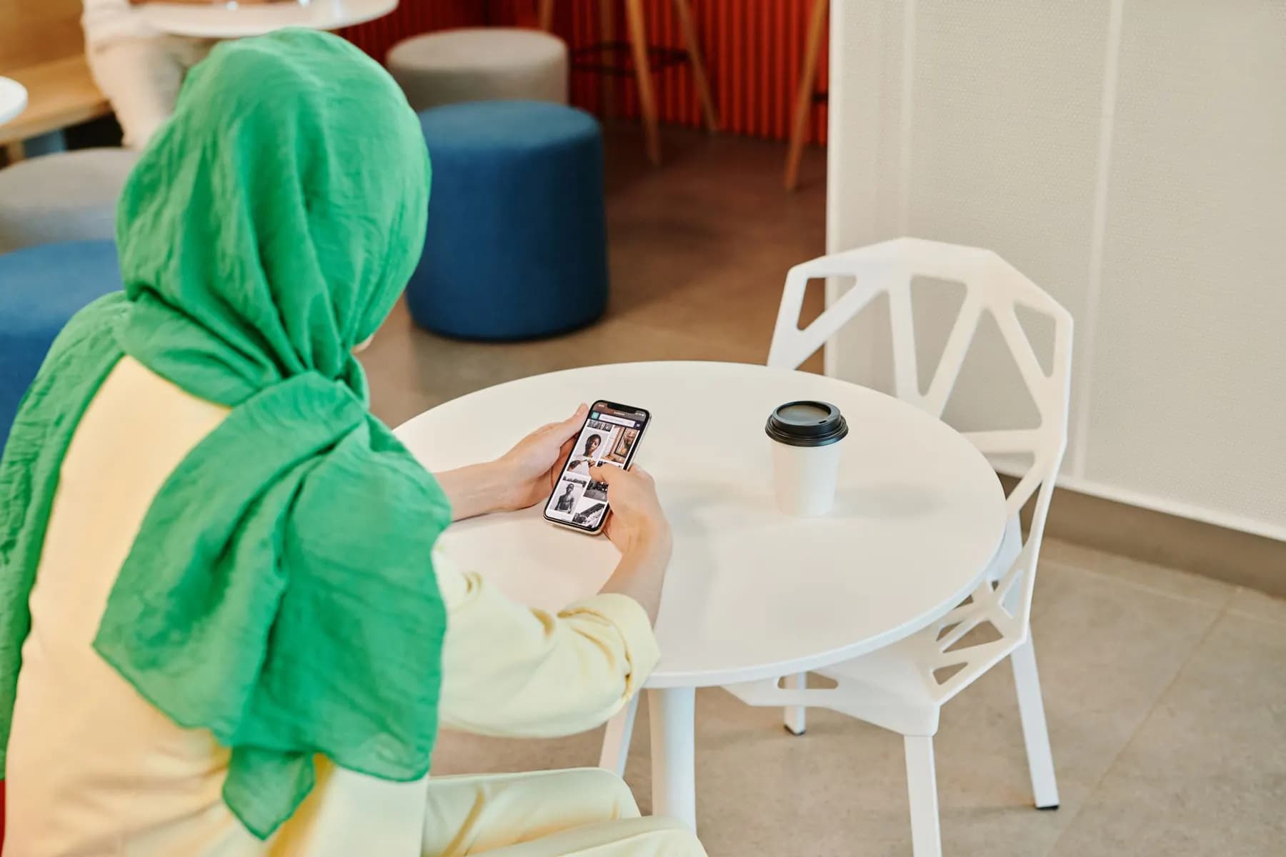 Un client derulând o aplicație de business pe telefon, la masa unei cafenele