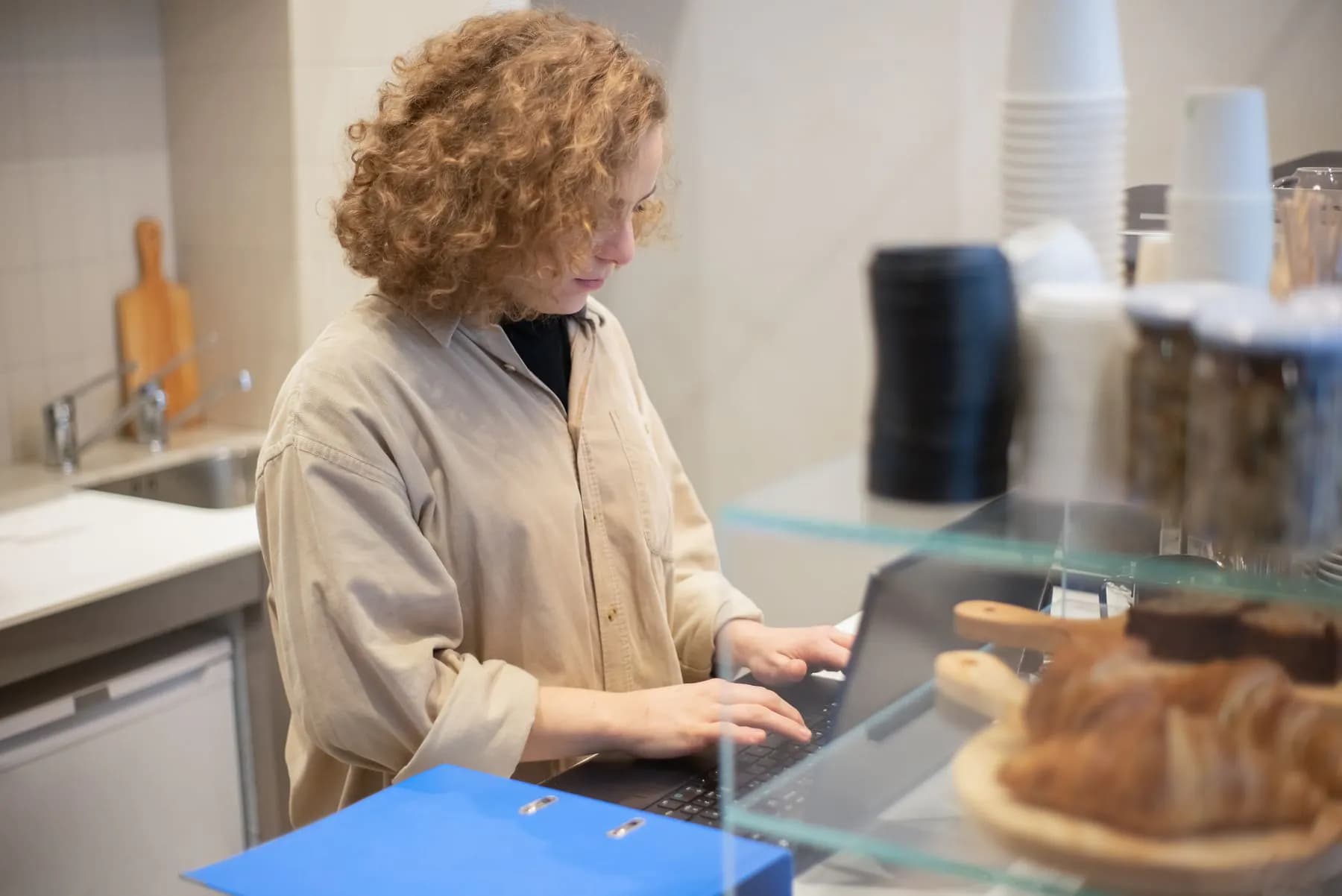 A café owner updating the business website on a laptop behind the counter