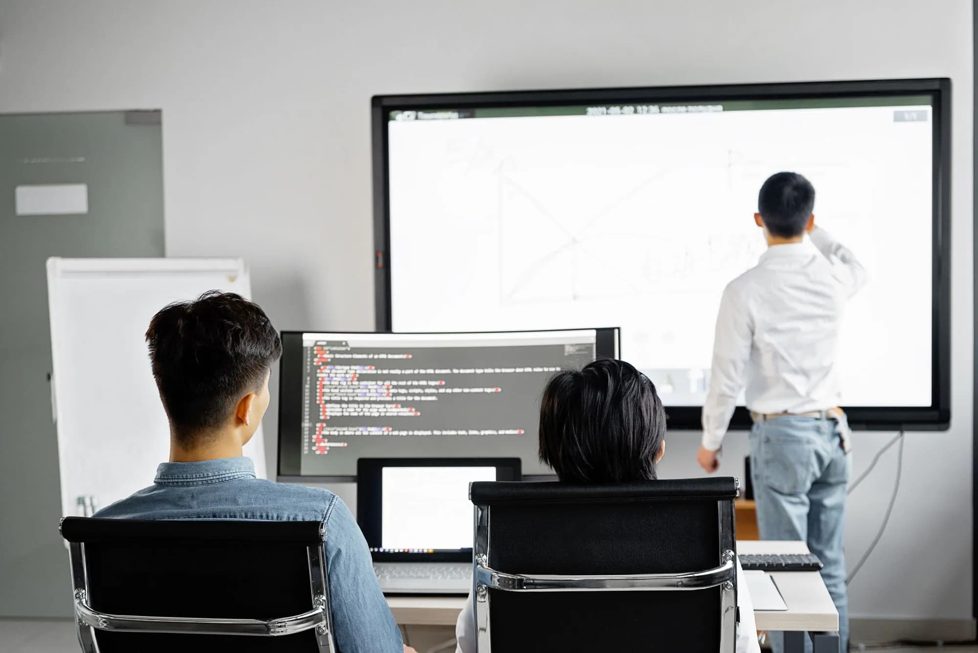 A development team gathered around a presentation screen in their office
