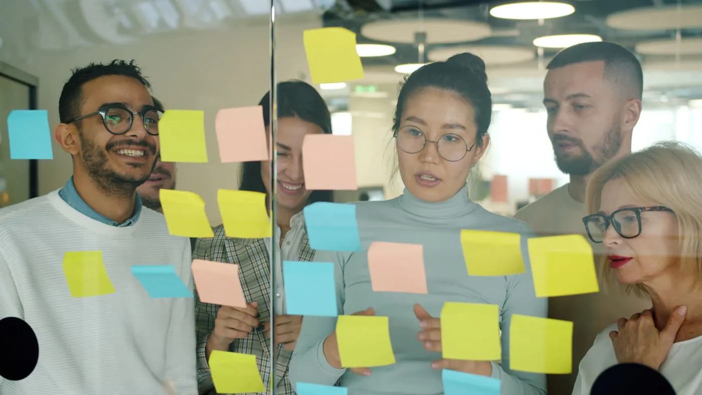 A team planning work with sticky notes on a glass wall