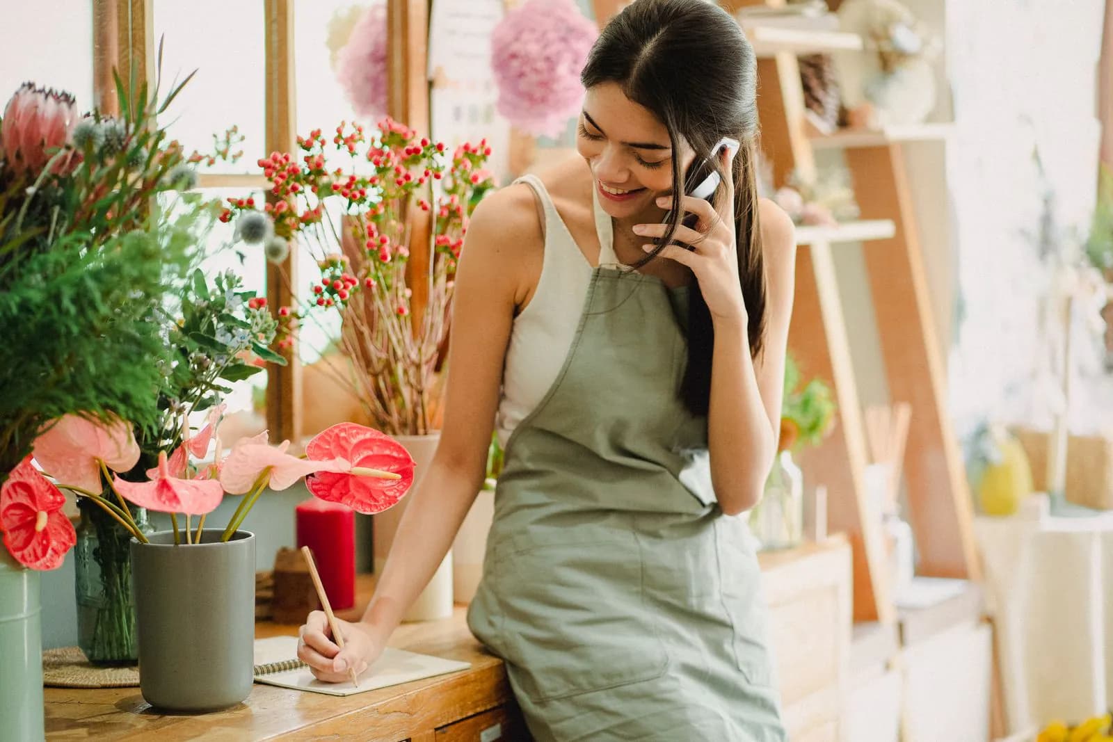 A florist in her shop taking an order by phone