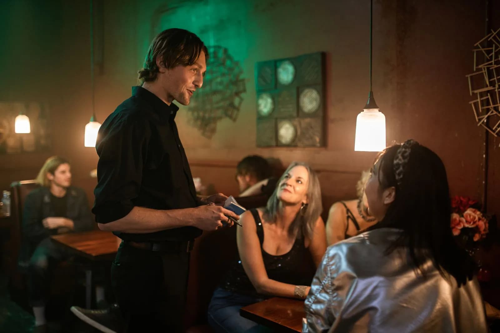 A busy restaurant at dinner, a waiter serving a full table
