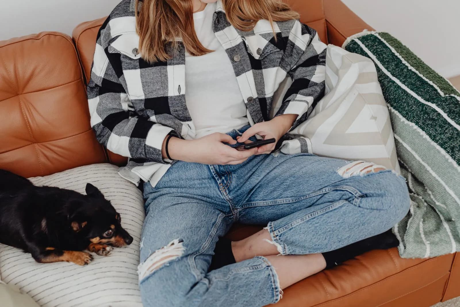 A young woman scrolling stories on her phone on the sofa