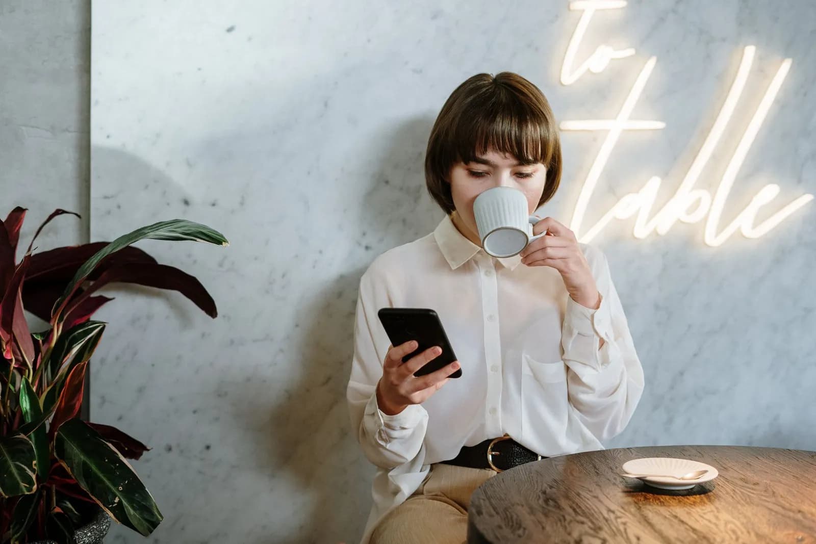 Une jeune femme lisant son téléphone devant un café