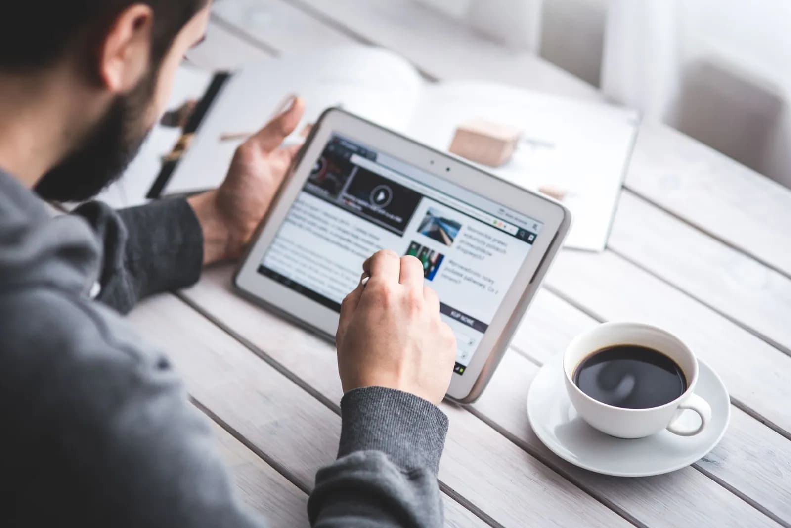 Un homme lisant sur une tablette devant un café