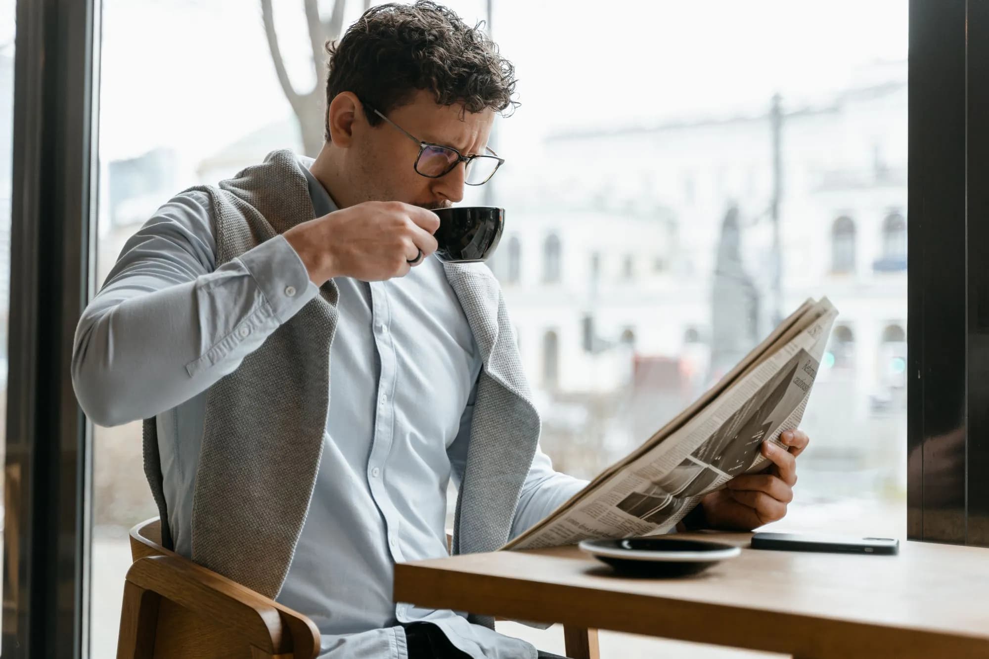 A man reading a newspaper over coffee in a cafe