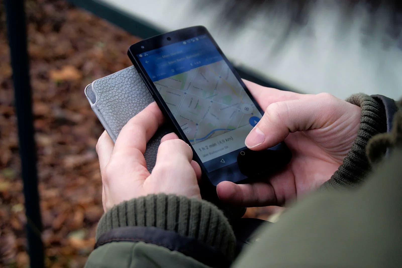 Mâini ținând un telefon cu o hartă deschisă, căutând un loc din apropiere