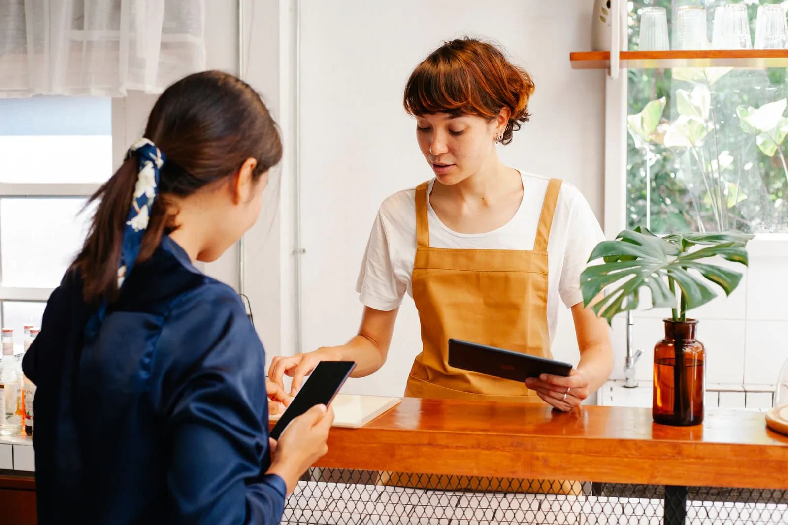 Un angajat de cafenea servind un client zâmbitor la tejghea