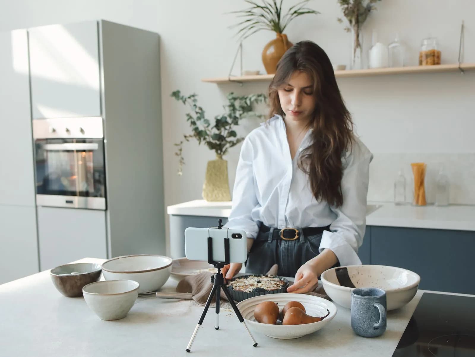 A woman recording a cooking video in her kitchen