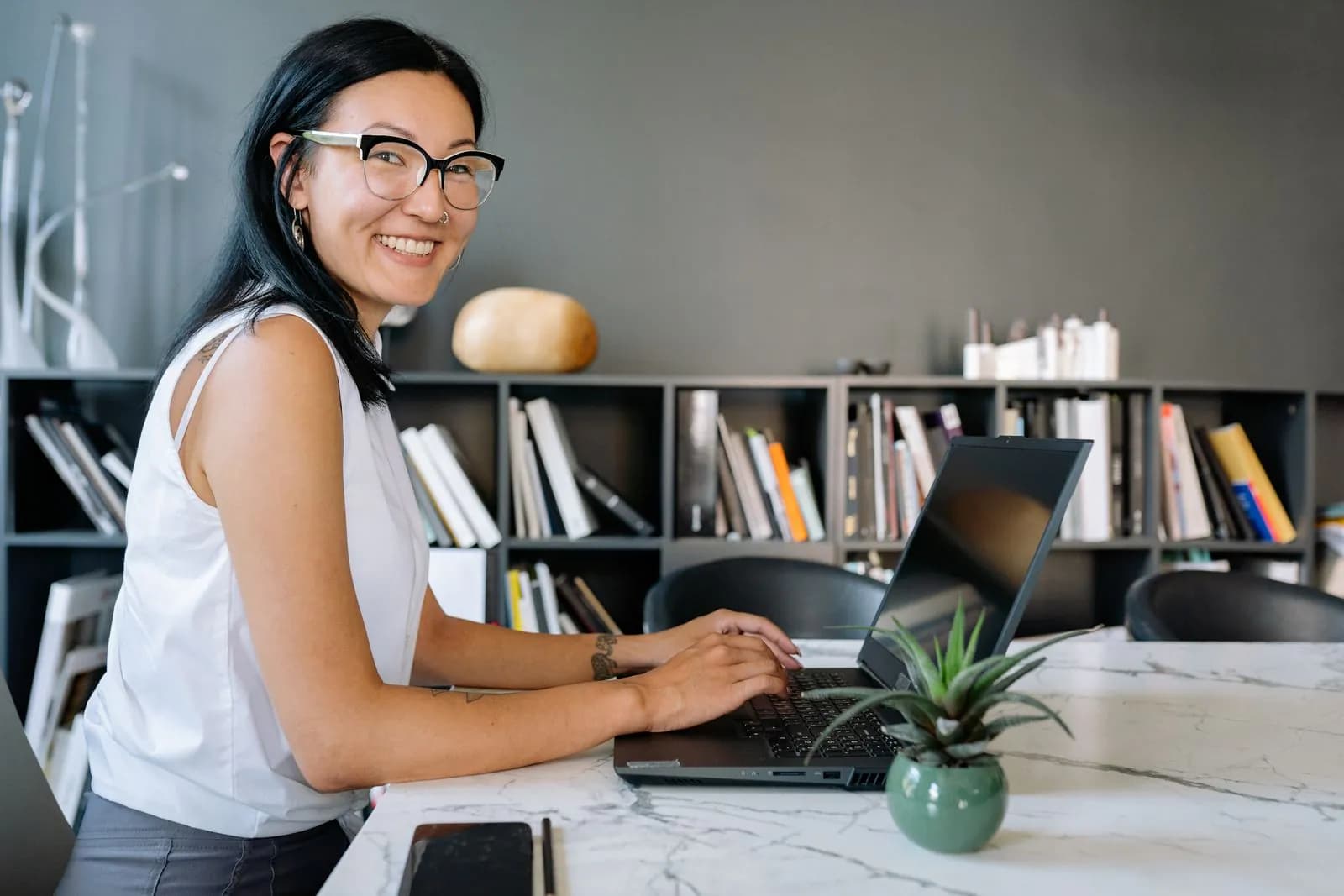 A smiling businesswoman working on a laptop in a bright office