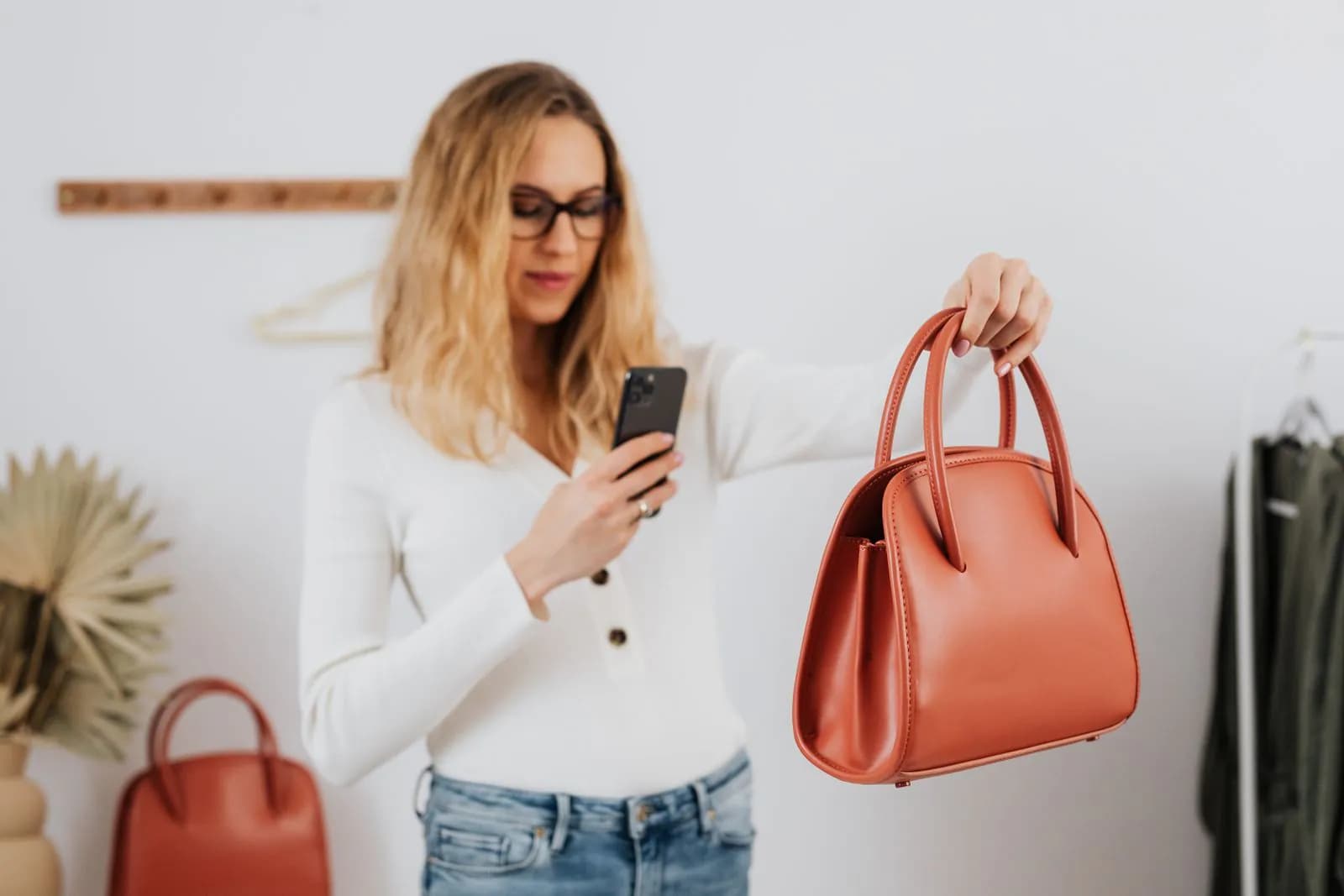 A shop owner photographing a leather handbag with her phone