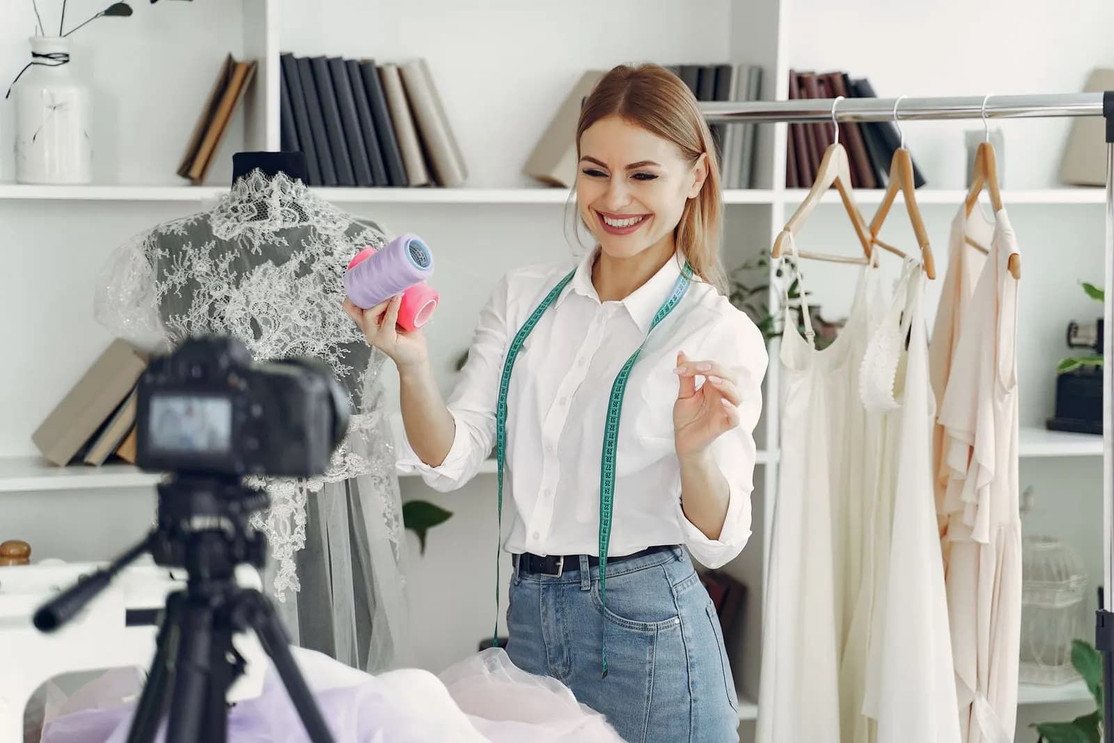 A smiling fashion designer recording a sewing tutorial in her workshop