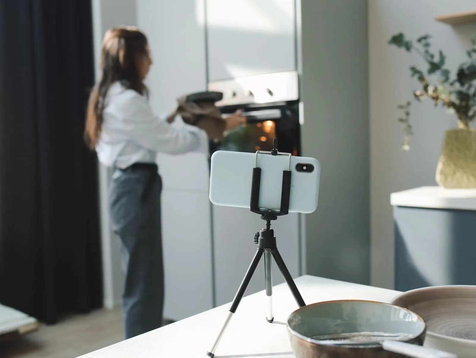 A woman filming her baking with a phone on a tripod in her kitchen