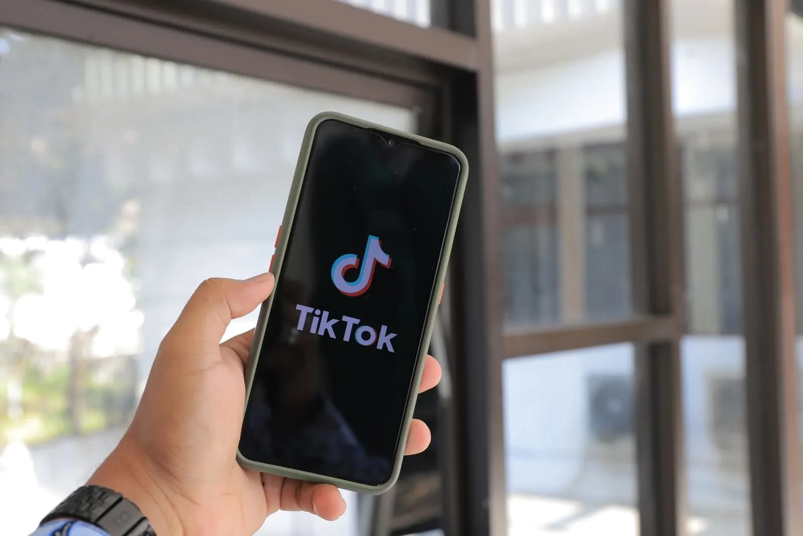 A hand holding a phone with the TikTok app open
