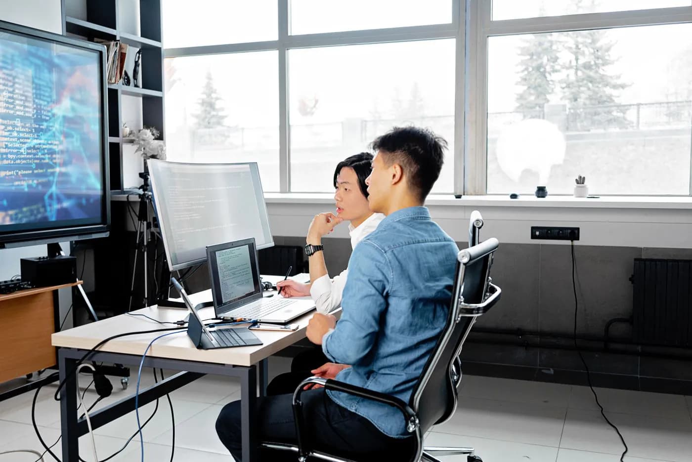 Two engineers reviewing code together on their screens