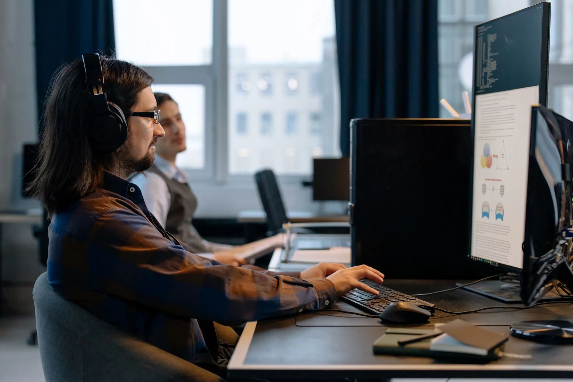 Two programmers working together at their desks in a modern office