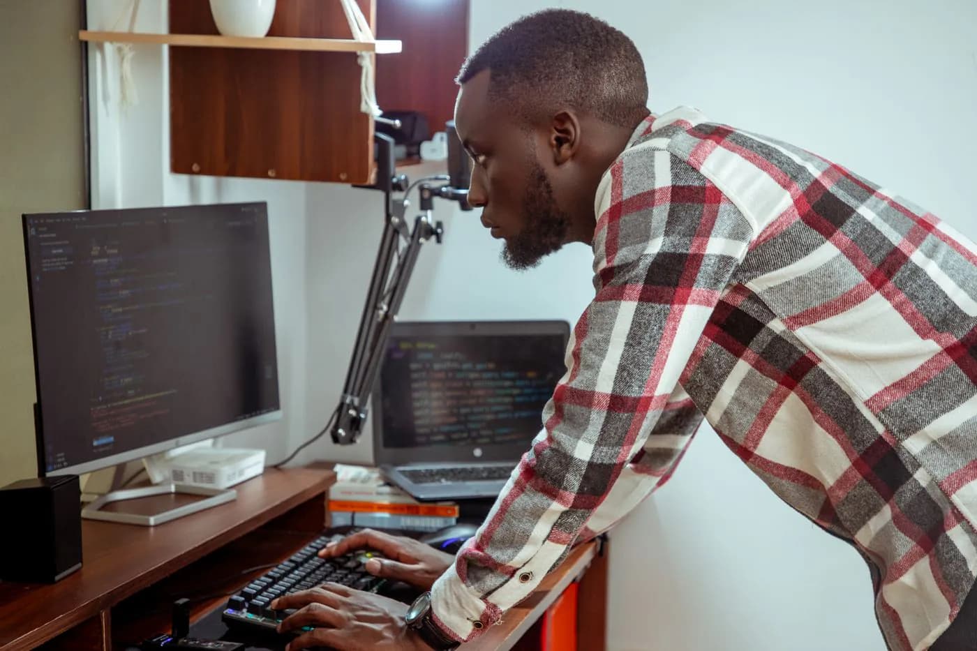 An engineer leaning over a computer to check a problem