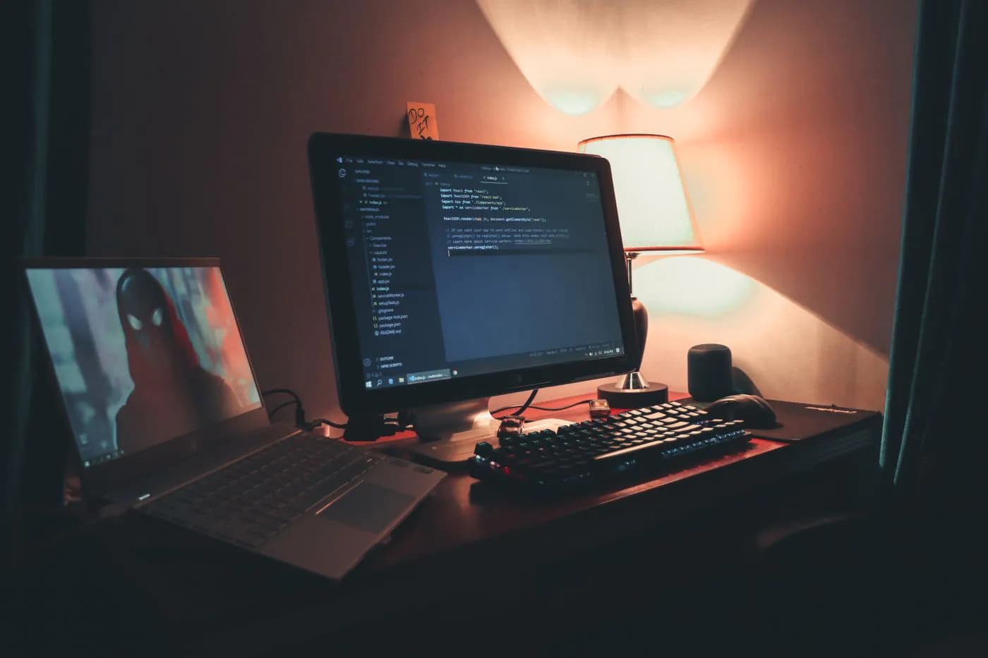Two screens of code on a desk in a warmly lit office