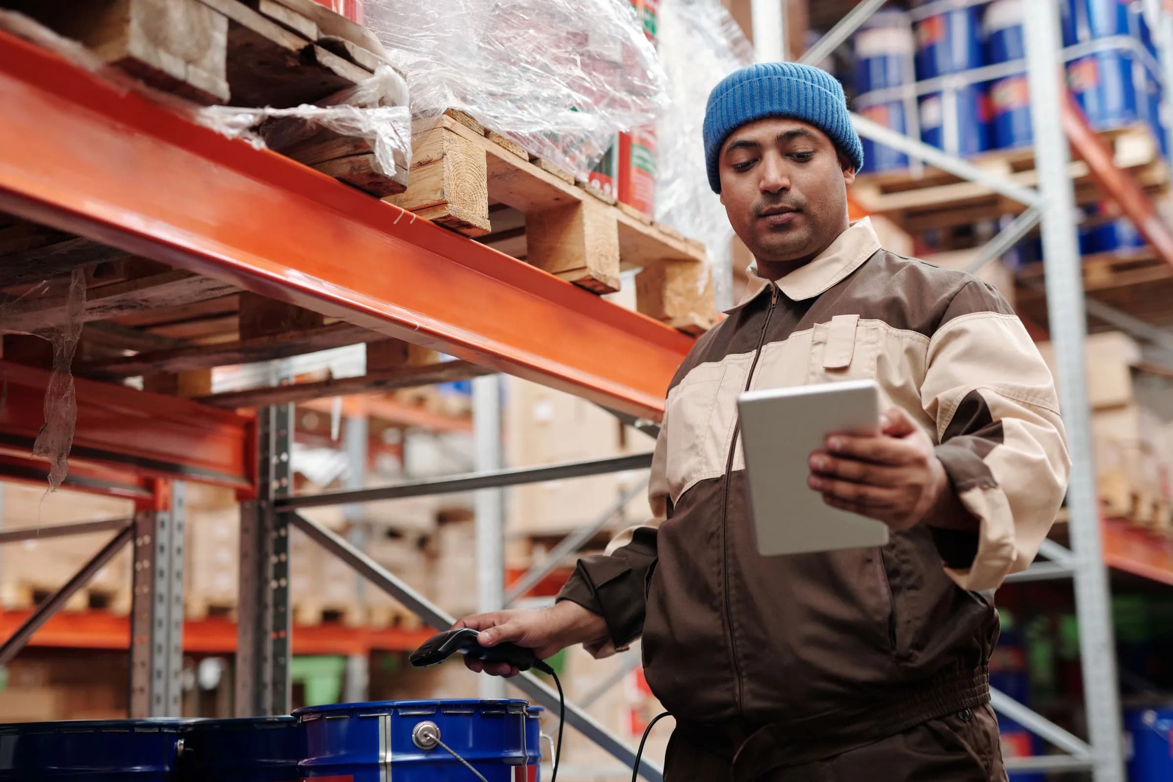 A warehouse worker checking stock on a tablet between the shelves