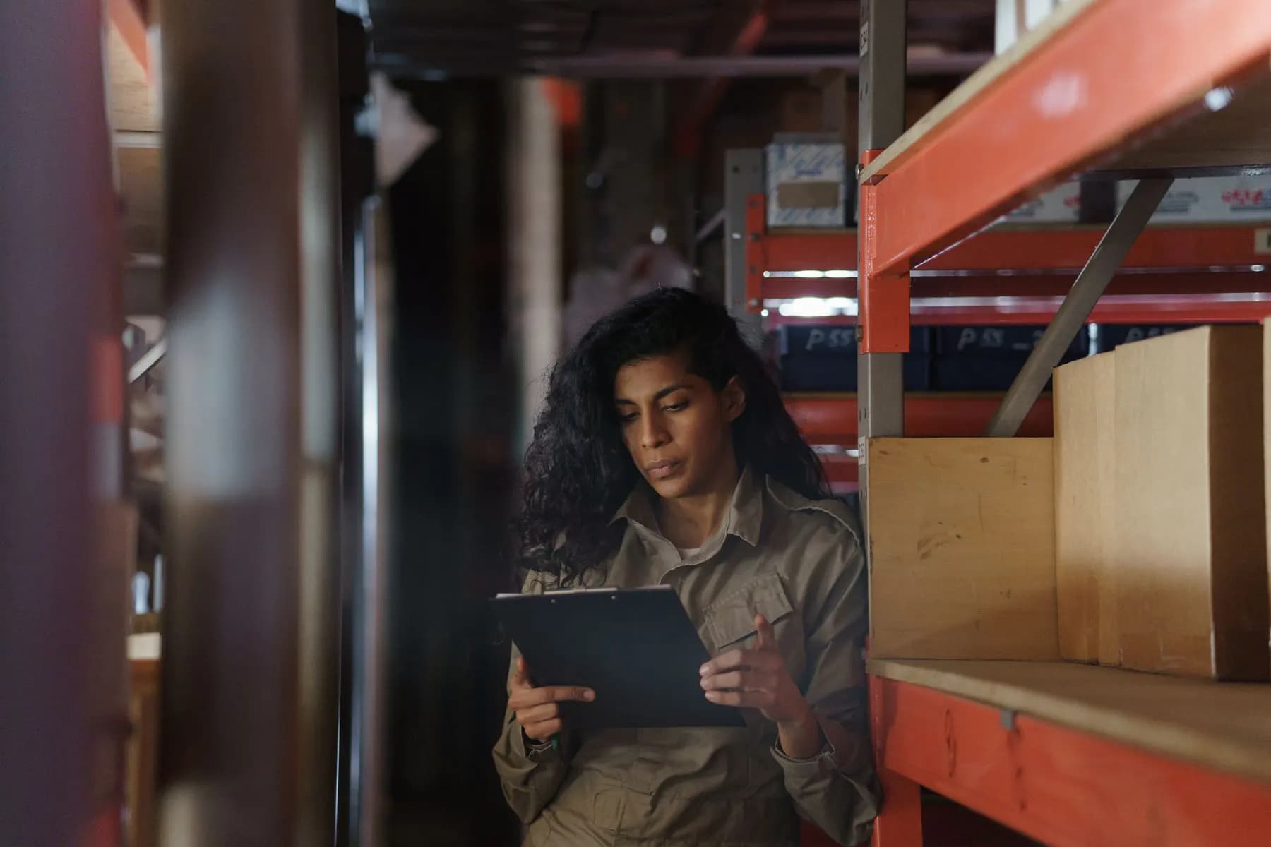 An operations manager taking stock between warehouse shelves
